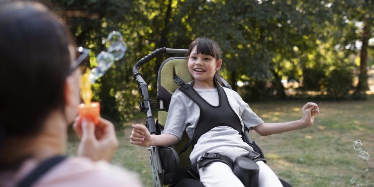Fotografía decorativa niña con discapacidad juega con burbujas